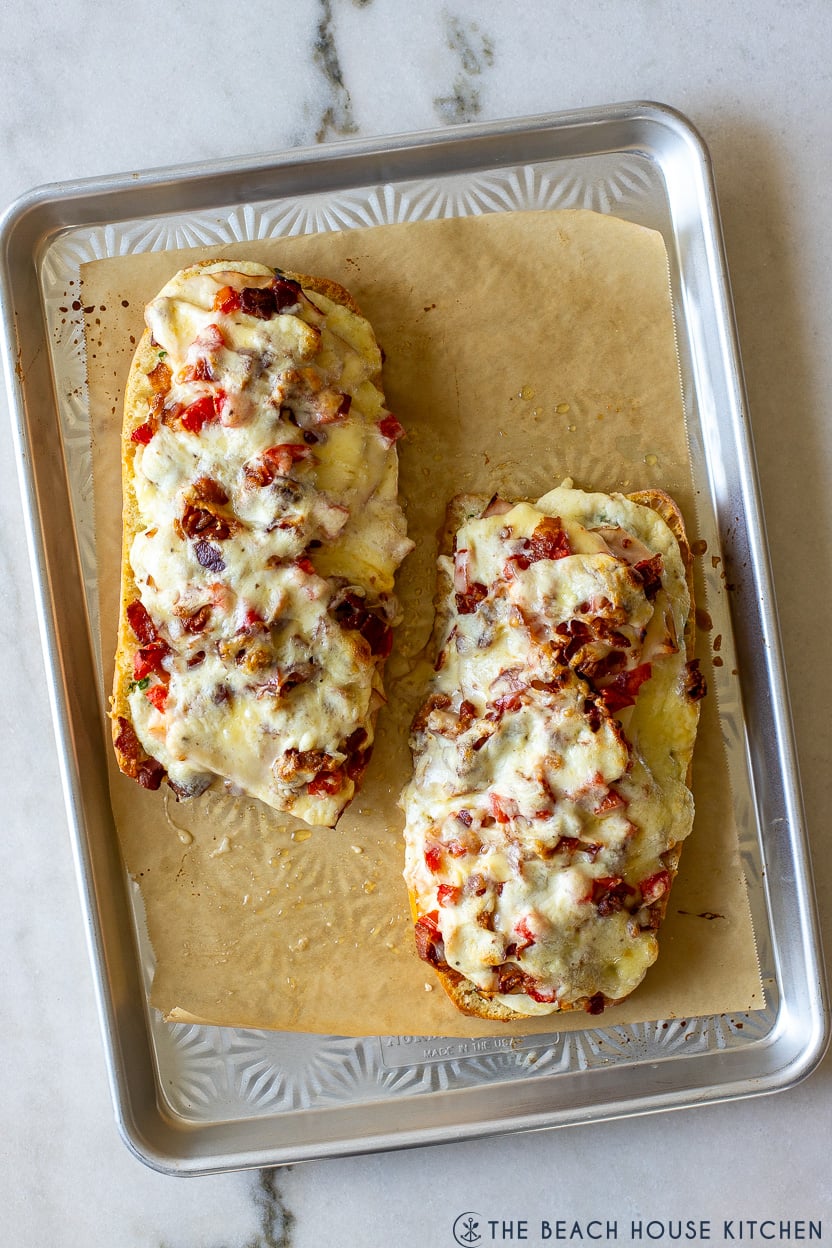 Overhead photo of two Kentucky Hot Brown Garlic Breads on a parchment-lined baking sheet
