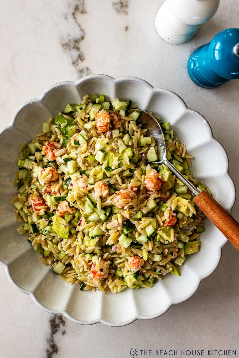 Overhead photo of a white scalloped bowl filled with lobster orzo salad with tarragon vinaigrete