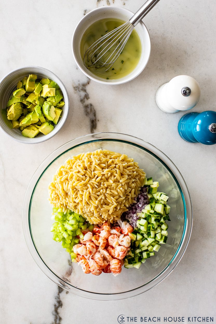 Overhead photo of a pre-mixed lobster orzo salad with a small bowl of chopped avocado