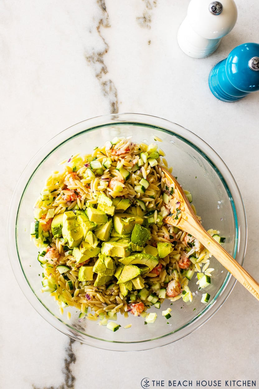 Overhead photo of a a bowl of orzo salad topped with chopped avocado