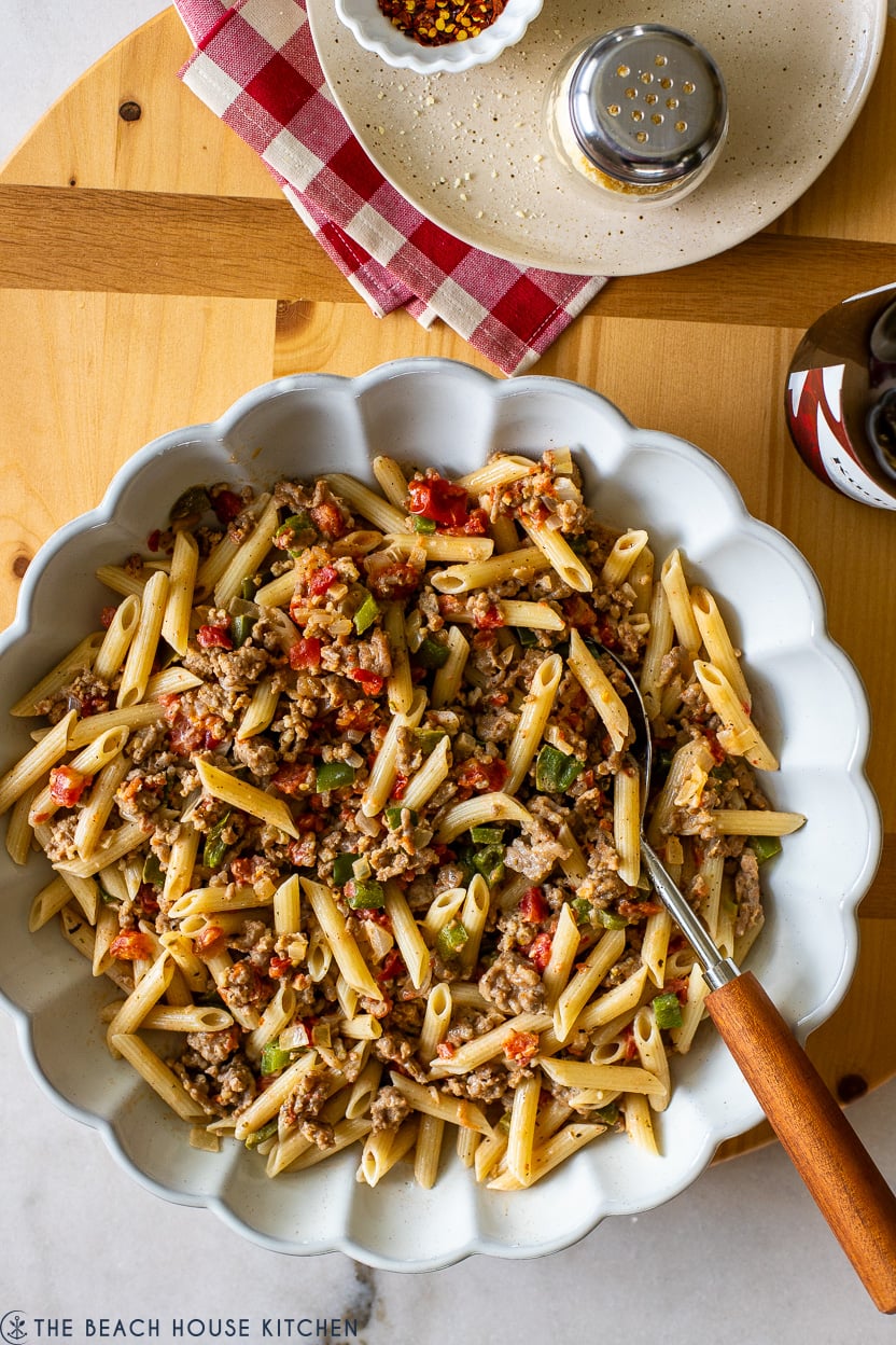 Overhead photo of a white scalloped dished filled with Penne with Italian Sausage Tomatoes Peppers and Onions