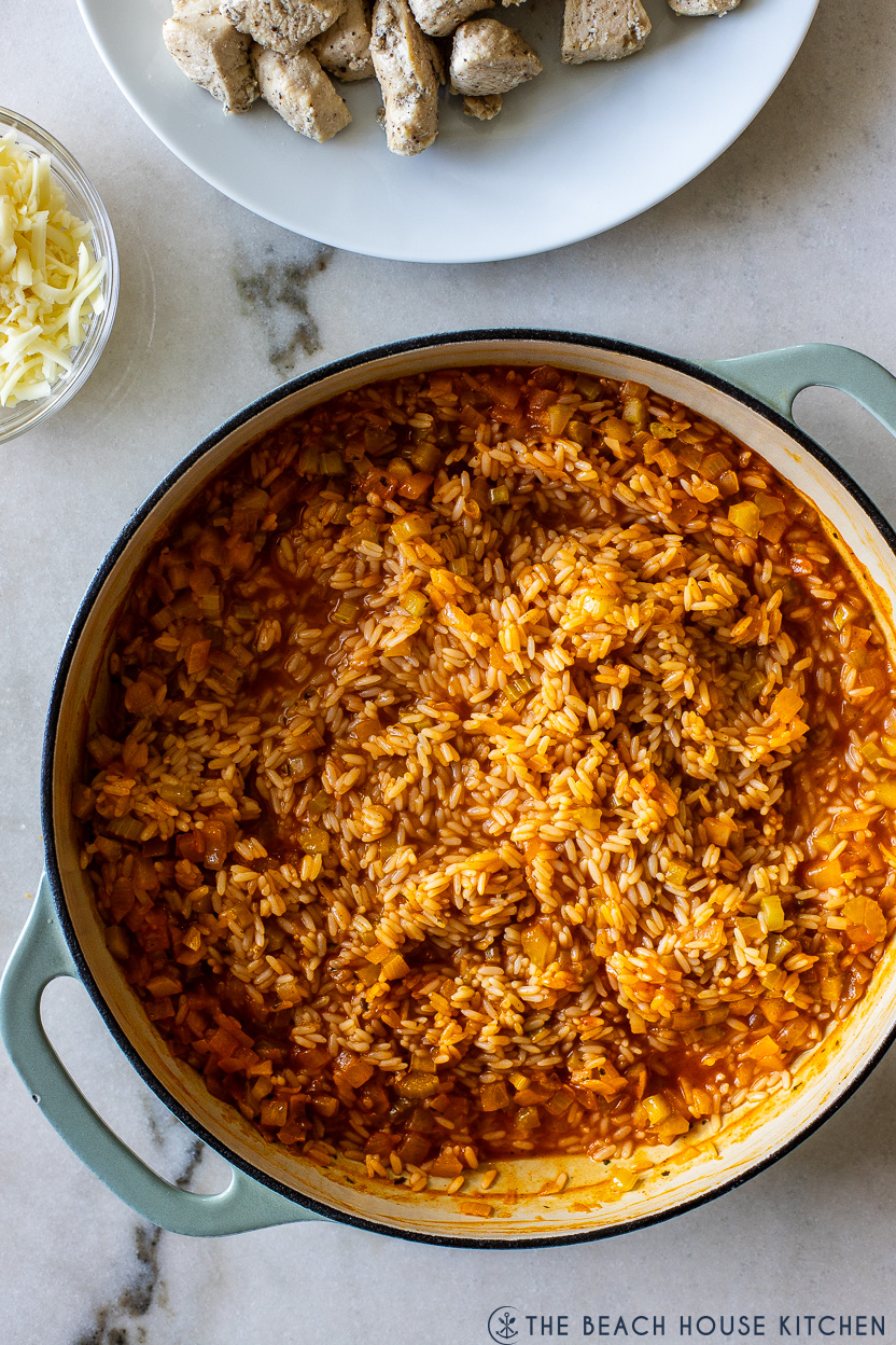 Overhead photo of a round cast iron dish filled with cooked rice with buffalo sauce