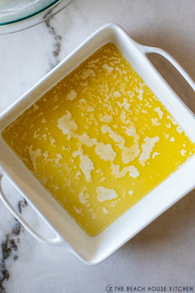 Up close overhead photo of a square baking dish filled with melted butter