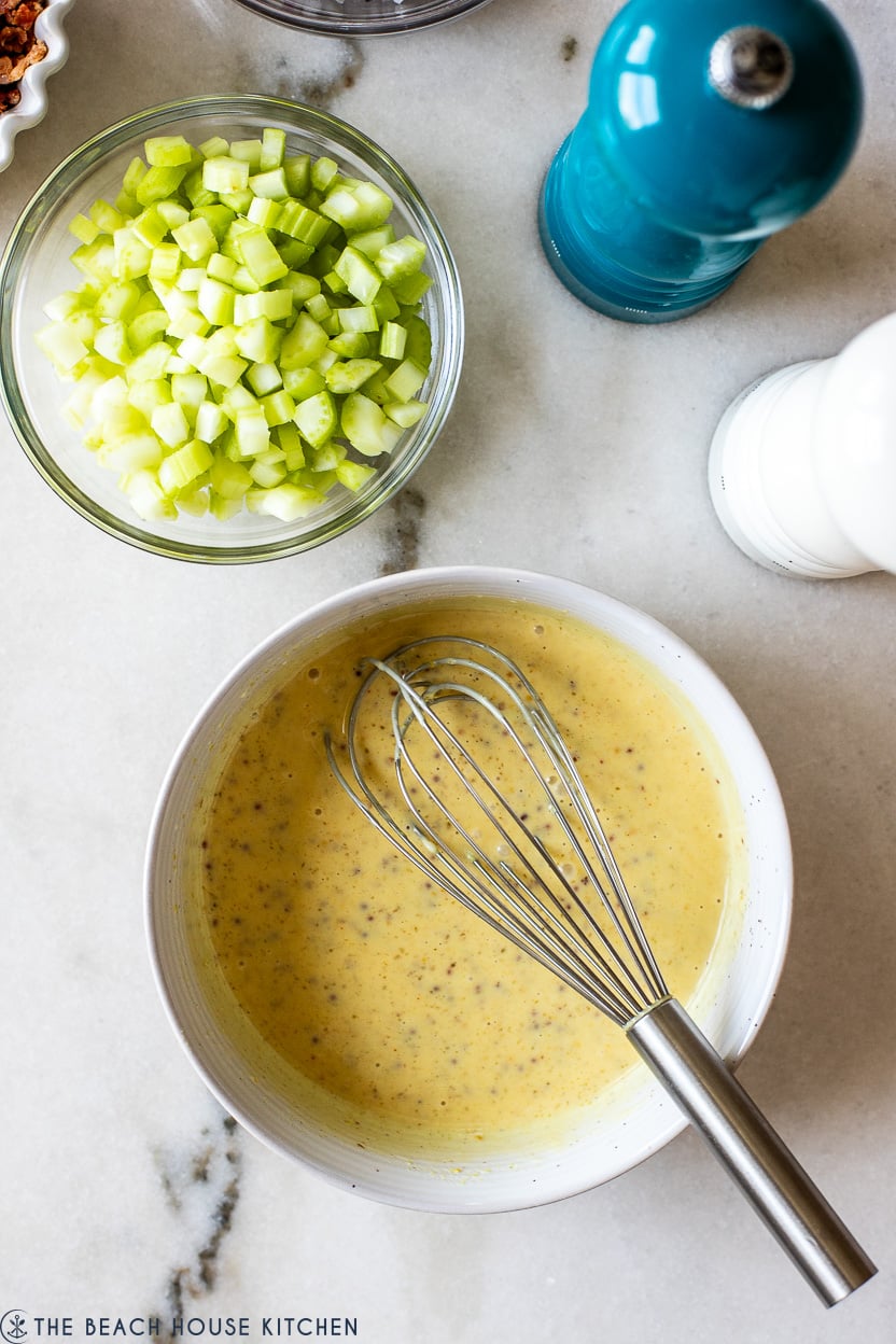 Up close overhead photo of a bowl of honey mustard dressing and a bowl of chopped celery