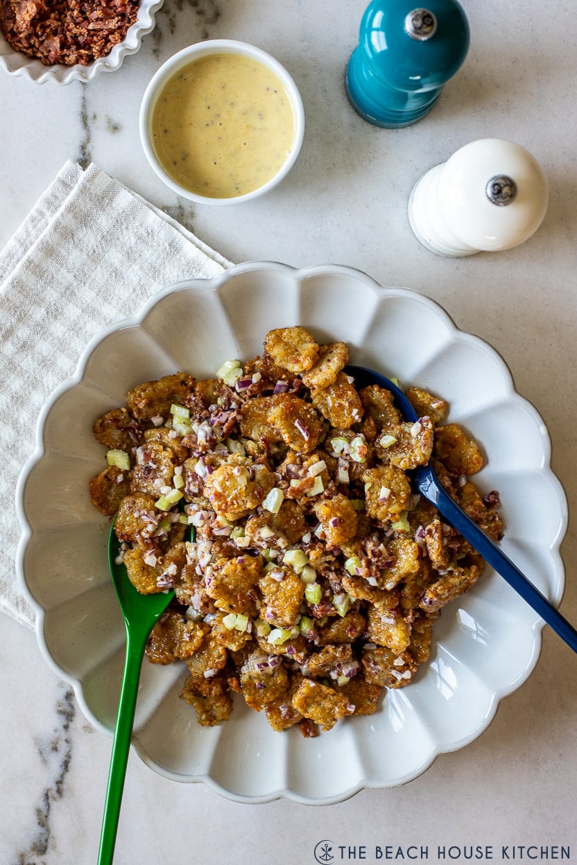 Overhead photo of a white scallped platter of honey mustard smashed tater tot salad