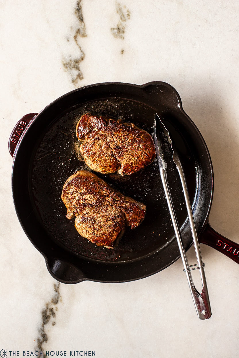 Overhead photo of a cast iron skillet with two filet mignon steaks