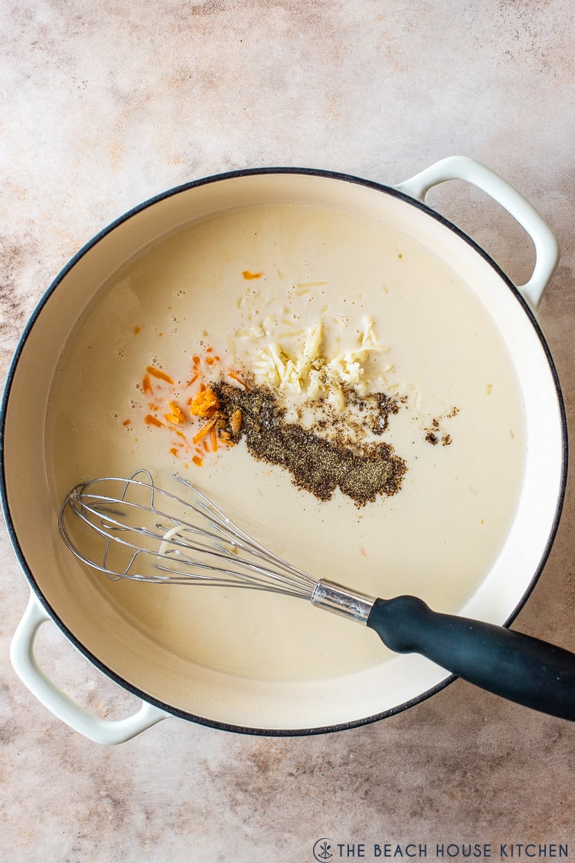 Overhead photo of a round skillet filled with a creamy sauce topped with pepper and shredded cheese
