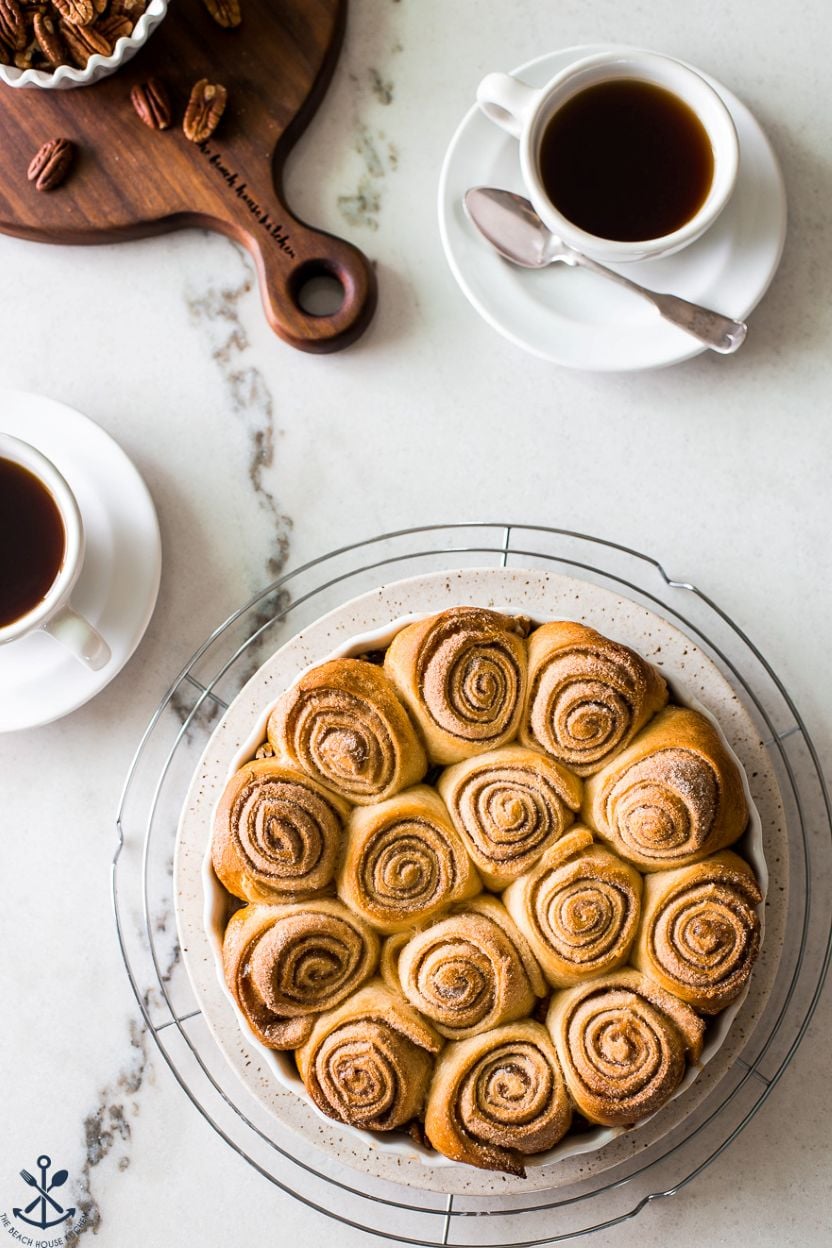 Overhead photo of a round baking dish on a wire rack filled with Easy Pecan Raisin Sticky Buns