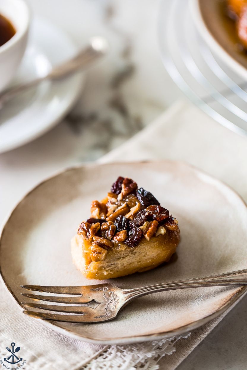 Up close photo of a pecan raisin sticky bun on a plate with a fork