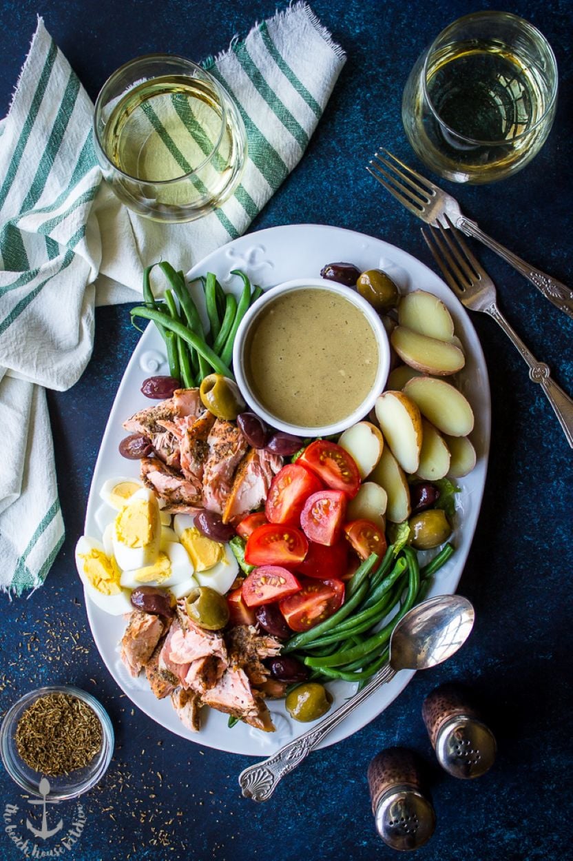 Overhead photo of a white oval platter topped with a Salmon Niçoise Salad with Dijon Vinaigrette