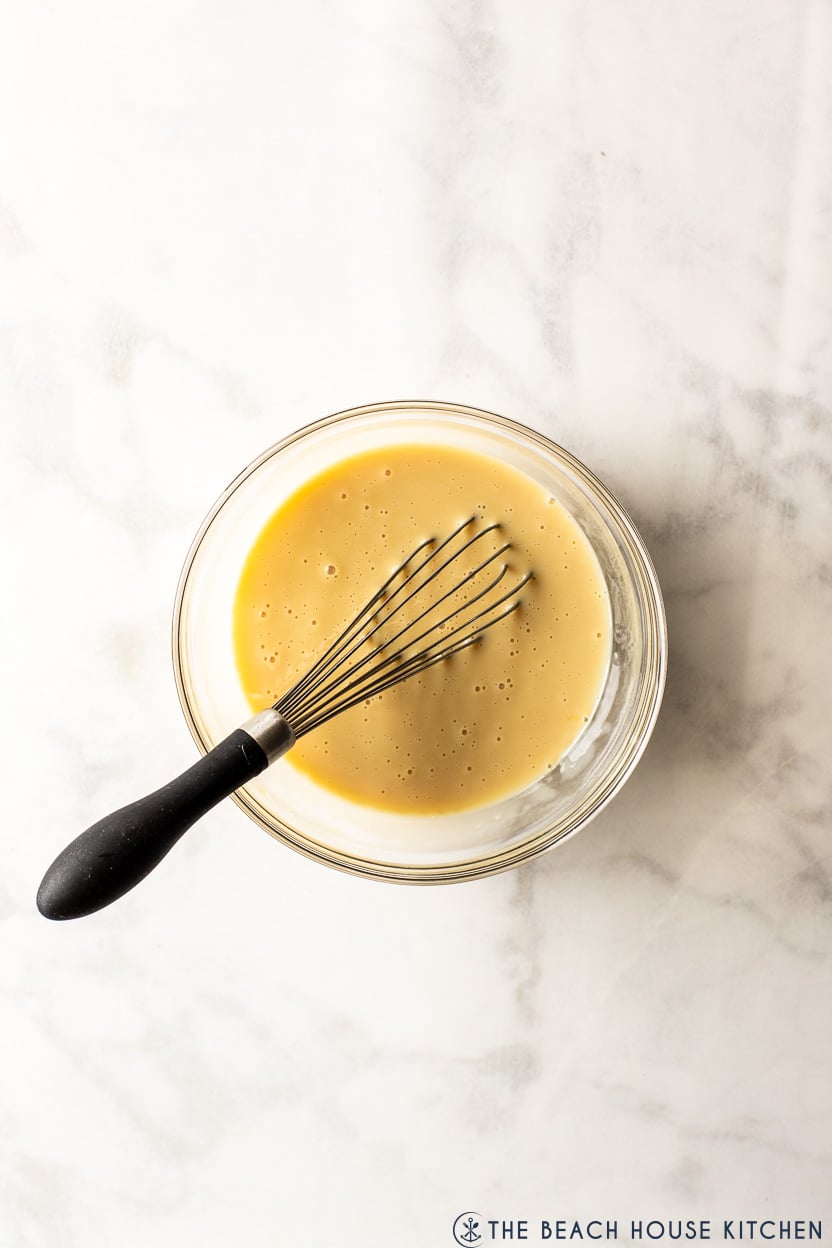 Overhead photo of a bowl of sweetened condensed milk with a whick in it