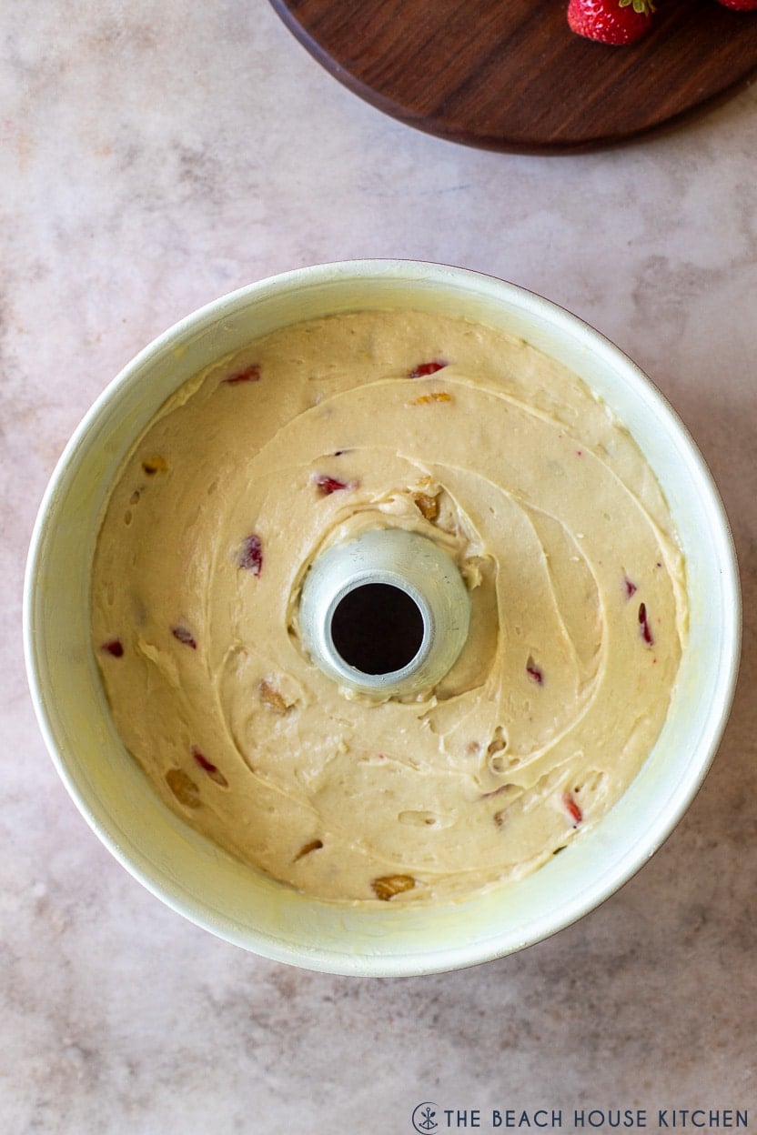 Up close overhead photo of a tube pan filled with strawberry mango pound cake batter