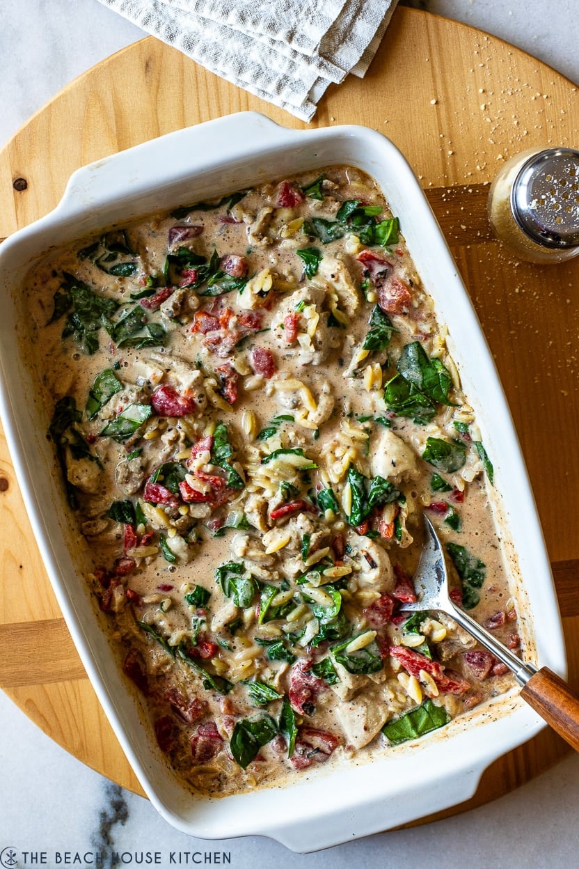 Overhead photo of a white dish of cheesy garlic and herb chicken with orzo