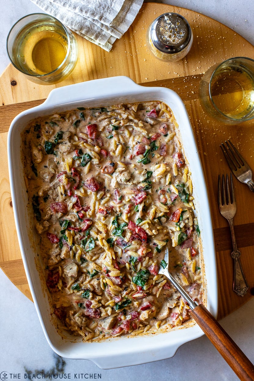 Up close overhead photo of Cheesy Garlic and Herb Chicken with Orzo in a white 9x13 baking dish