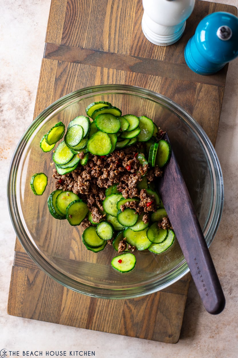 Overhead photo of a glass bowl filled with ground beef and cucumbers