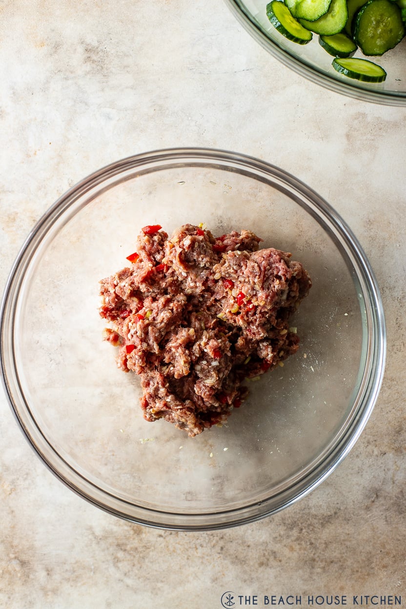 Overhead photo of raw seasoned ground beef in a glass bowl