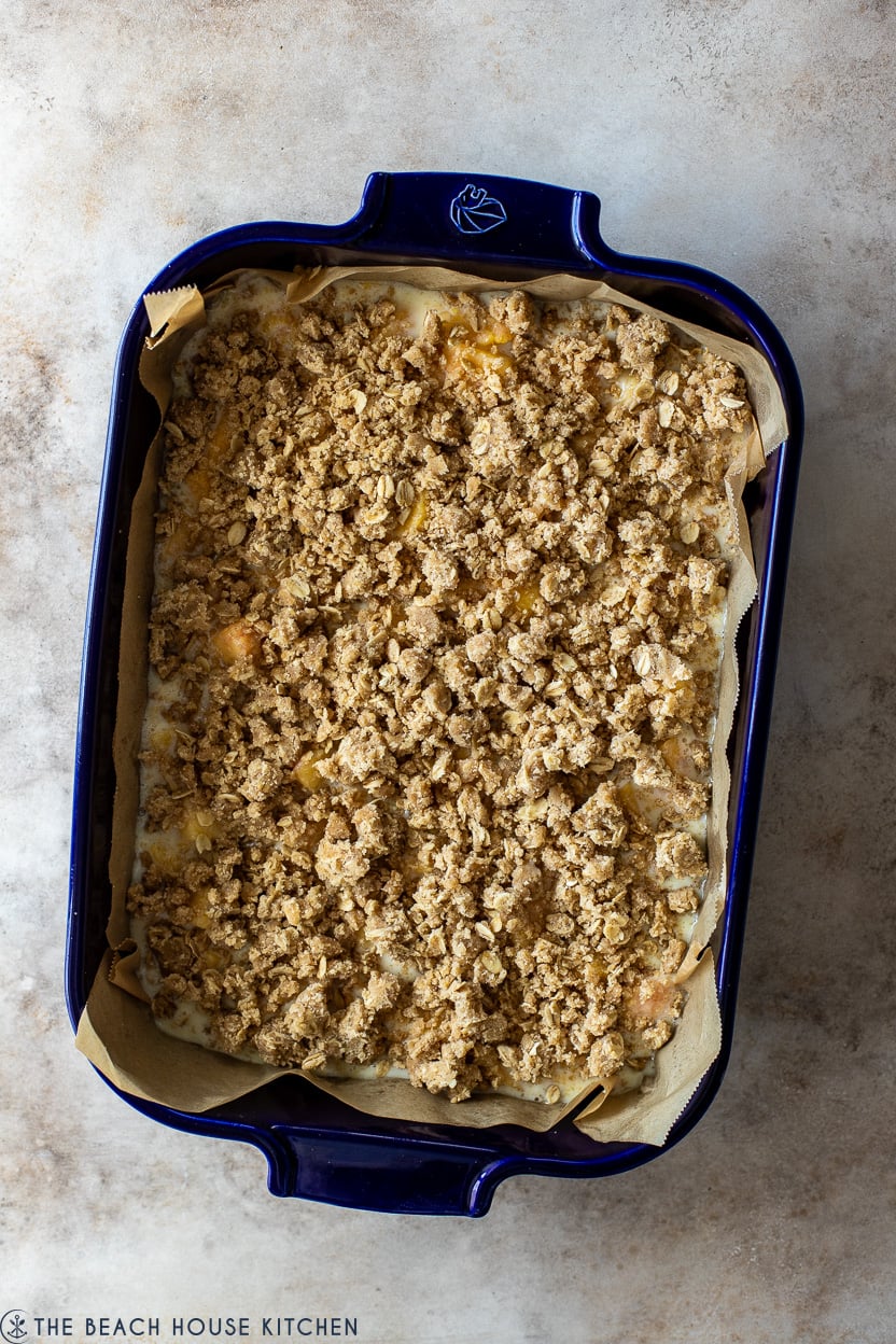 Overhead photo of streusel topped peach bars in a blue baking dish