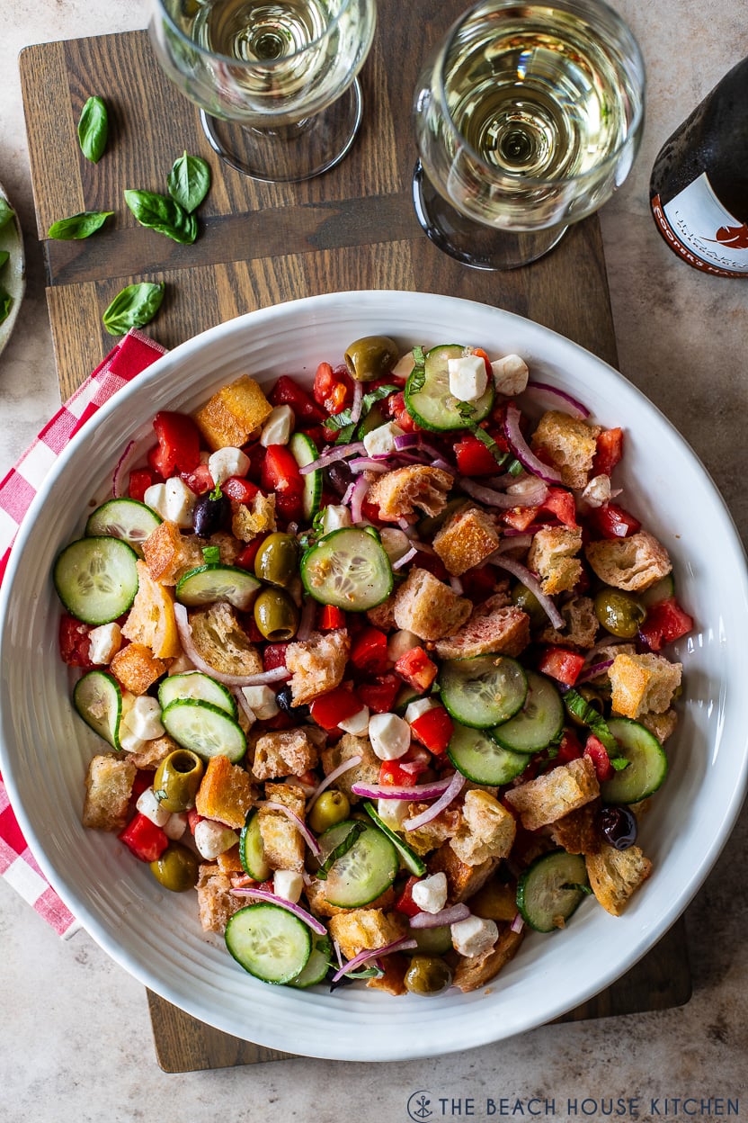 Overhead photo of a fresh panzanella salad in a large white serving bowl