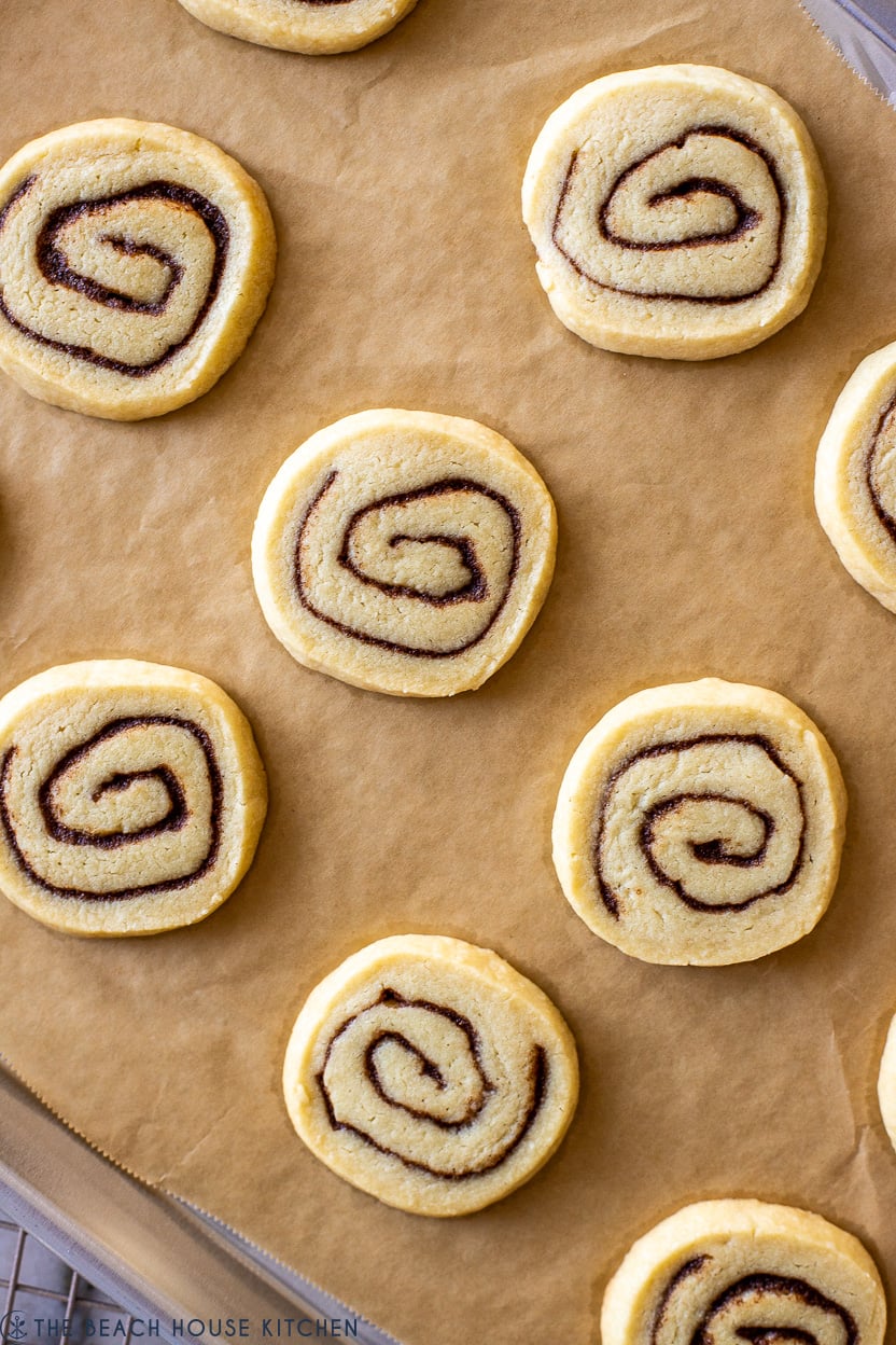 Up close overhead photo of cinnamon roll cookies on a parchment-lined sheet