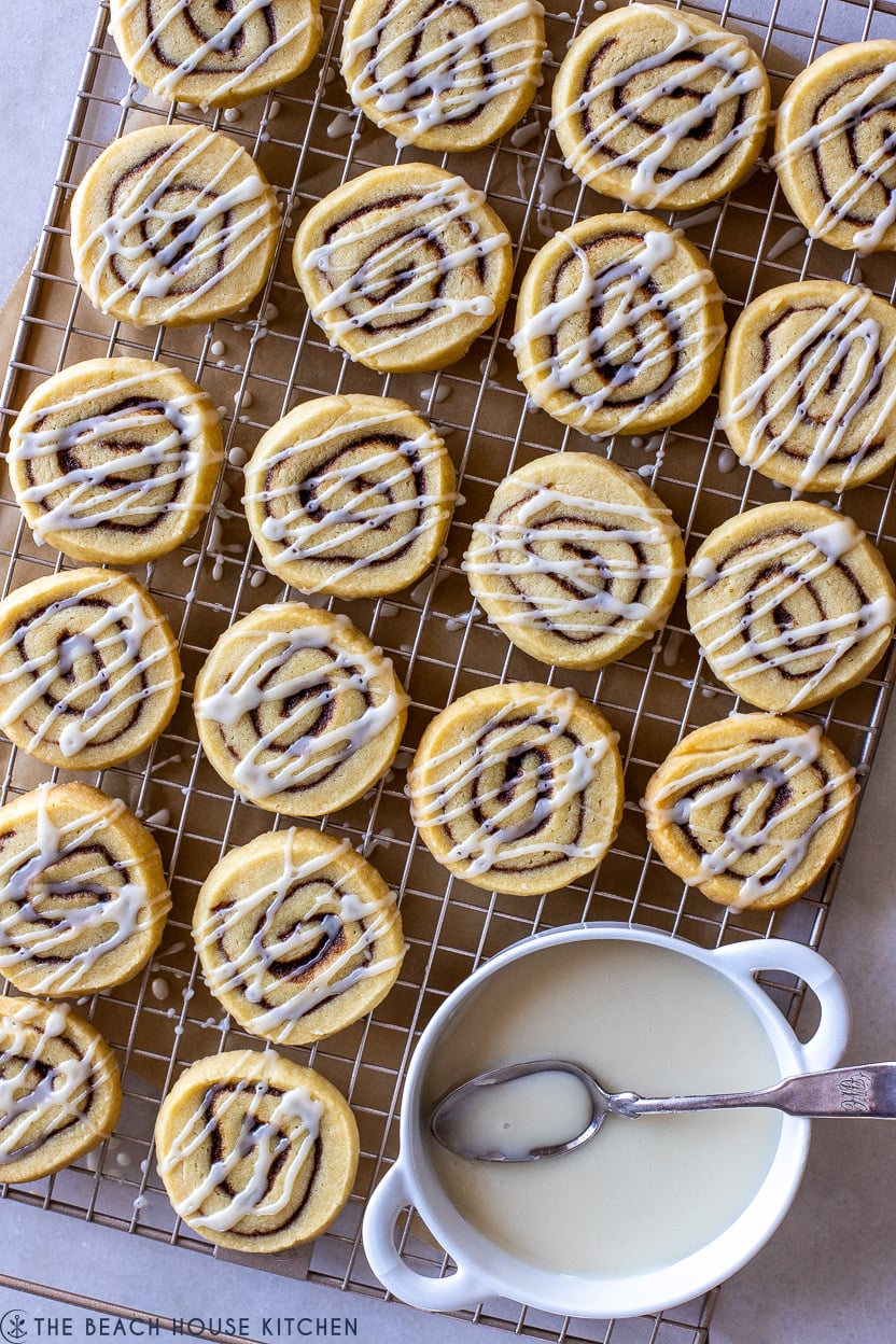 Overhead photo of glazed cinnamon roll cookies on a wire rack