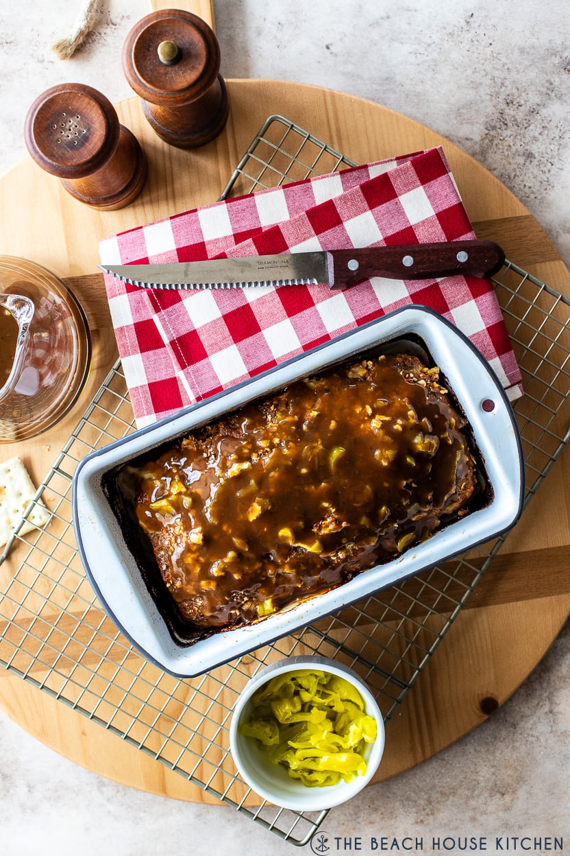 Overhead photo of a Mississippi Meatloaf in w white loaf pan on a wire rack with a sharp knife