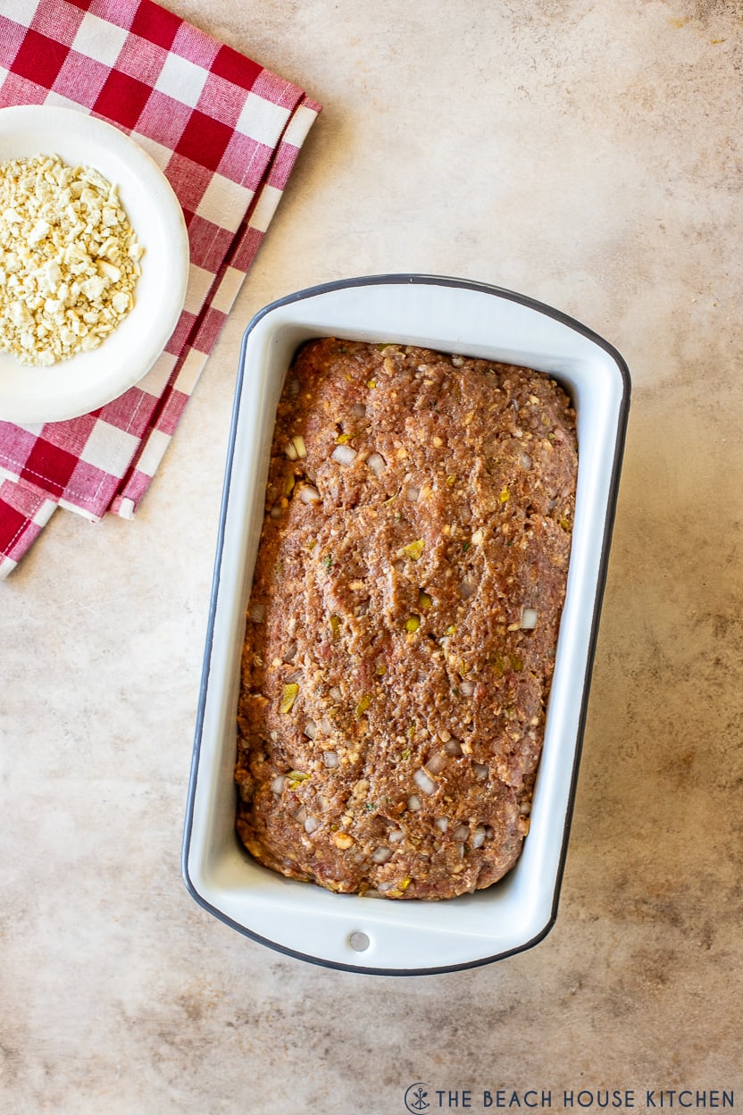 Overhead photo of a pre-baked meatloaf in a white loaf pan