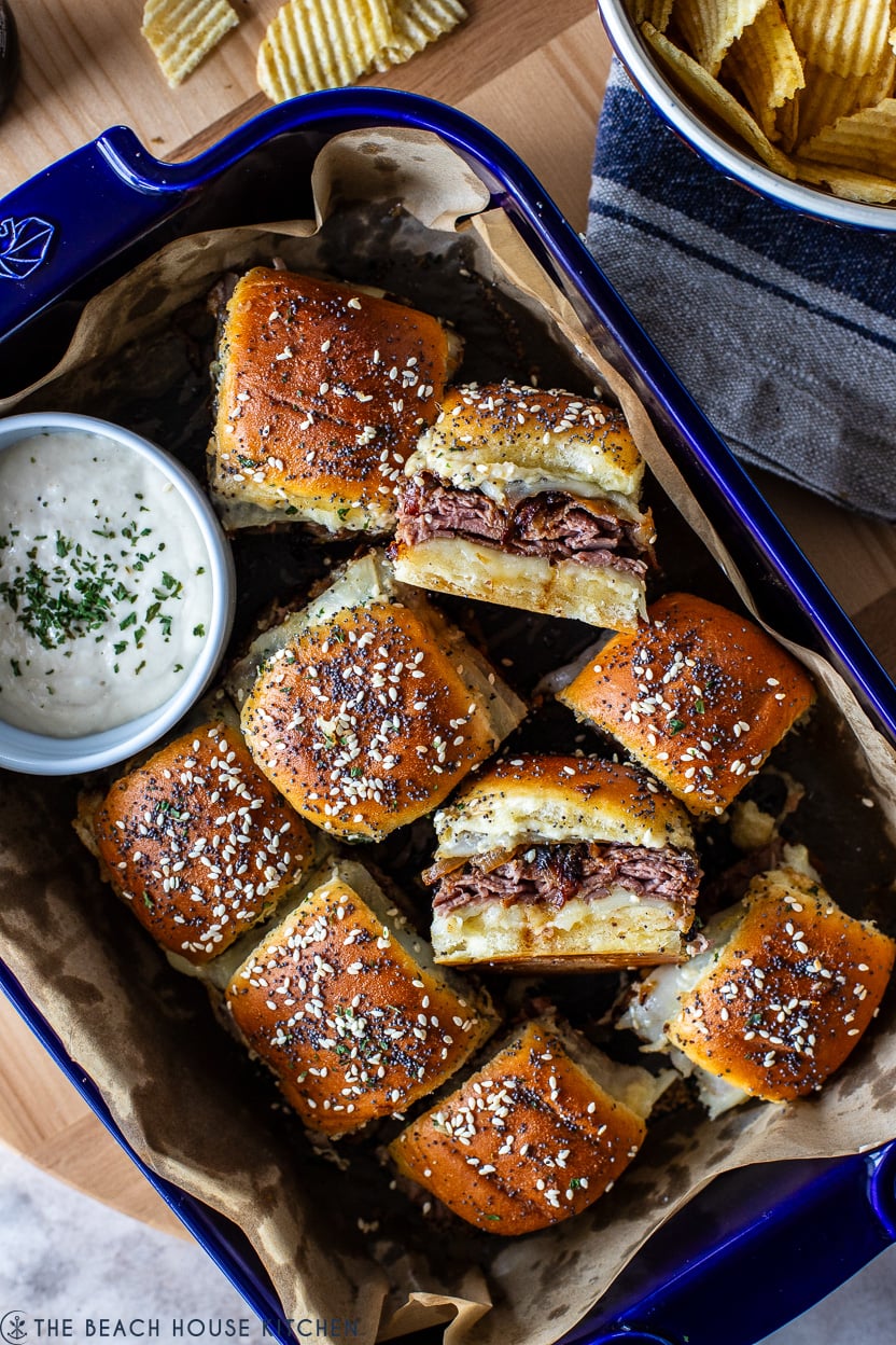 Overhead photo of a blue baking dish filled with Roast Beef Sliders with Caramelized Onions and Horseradish Sauce