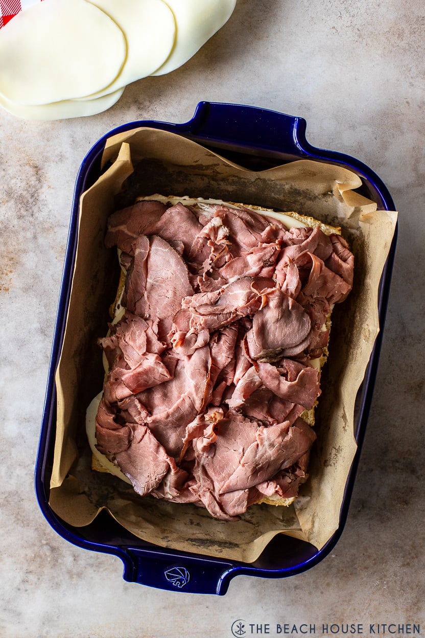 Overhead photo of roast beef sliders in a blue baking dish