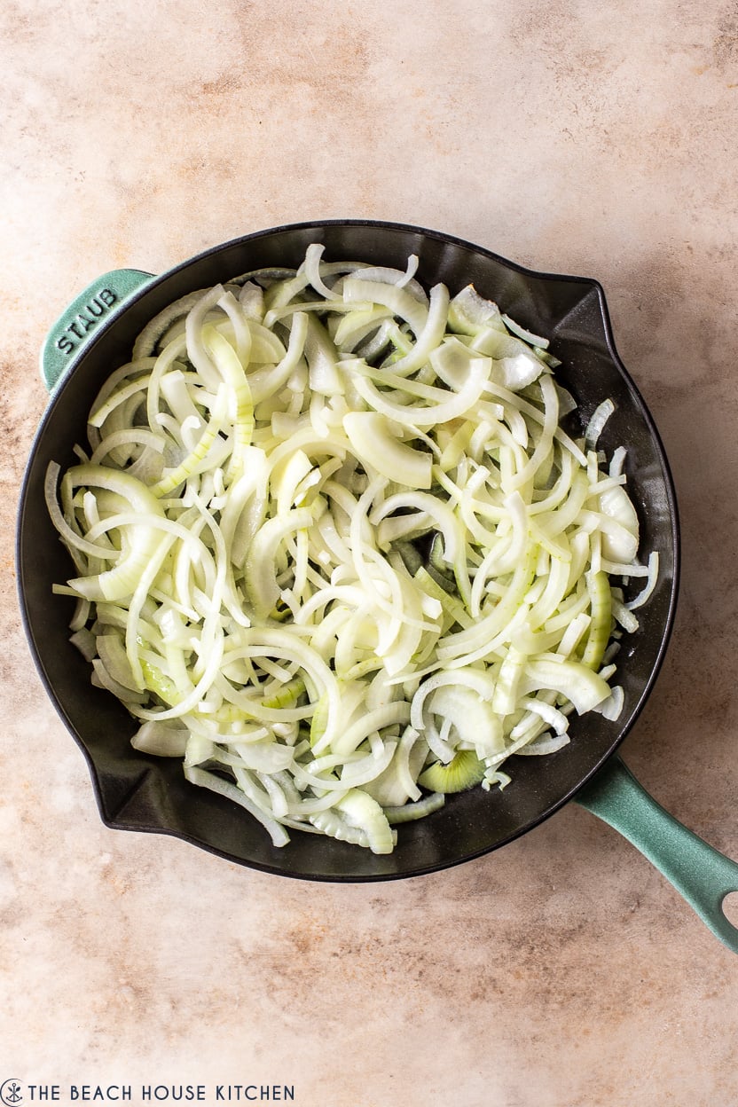 Overhead photo of a skillet of pre-cooked sliced onions